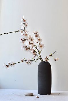 a black vase with white flowers in it