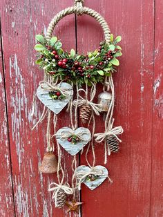 a red door with a wreath and bells hanging from it's side on a rope