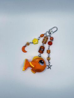 a keychain with a fish and beads hanging from it's side on a white surface