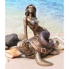 a statue of a woman sitting on top of a turtle next to some seashells