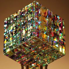 a multicolored glass cube on top of a metal pole in front of a brown background