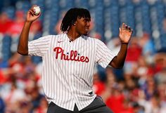 a baseball player is throwing a ball in the air with his hand out to catch it