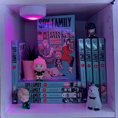 a shelf filled with books and toys on top of each other in front of a purple light