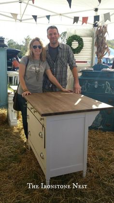 a man and woman standing in front of a kitchen island with a butcher block top