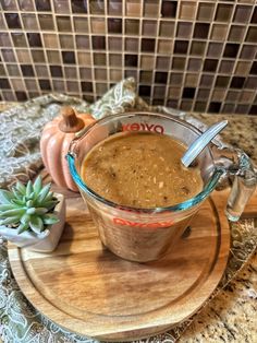 there is a bowl of soup on the table with some succulents next to it