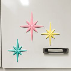 three star magnets on the back of a refrigerator door, one has a black handle