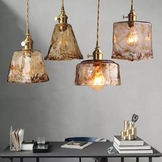 three glass pendant lights hanging over a table