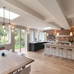 an open kitchen and dining room with wood flooring, white walls and ceiling lights