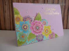 a card with flowers on it sitting on top of a white table next to a wooden wall