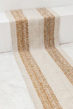 a white and brown striped rug sitting on top of a floor next to a wall