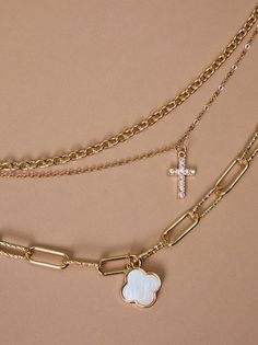 Faith and fashion meet in this layered necklace. Three delicate chains showcase a shimmering mother-of-pearl clover, a golden cross, and sparkling crystals, offering a statement piece for any occasion. Layered Cross Necklace, Golden Cross, Cross Necklaces, Floral Shop, A Cross, Mini Dress Shop, Accessories Jewelry Necklace, Altar'd State, Layered Necklace