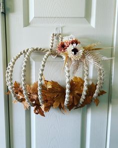 a white door with three wreaths hanging from it's side and two flowers on top