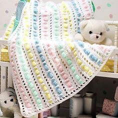 there is a crocheted baby blanket on top of a crib next to stuffed animals