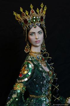 a close up of a doll wearing a green dress and tiara with jewels on it's head