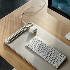 a computer keyboard sitting on top of a wooden desk next to a mouse and monitor