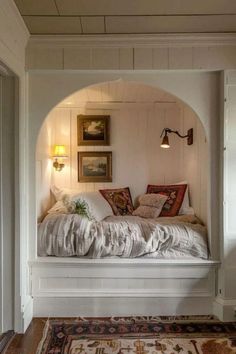 a white bed sitting under a window next to a rug