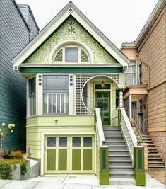 a green and white house with stairs leading up to it