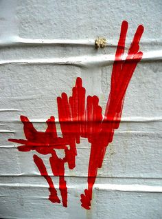 a painting on the side of a building that has red paint splattered on it