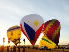 several hot air balloons in the shape of flags are being flown at an airshow