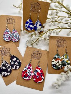 four pairs of flower print tear earrings are shown in front of a card and some flowers