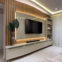 a living room with white furniture and a large flat screen tv mounted on the wall