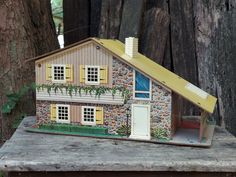 a doll house sitting on top of a wooden table next to a tree and fence