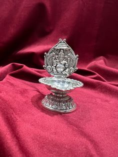 a silver vase sitting on top of a red cloth