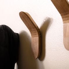 a wooden coat hook on the wall next to a black jacket hanging from it's side