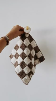 a hand holding a brown and white checkered towel