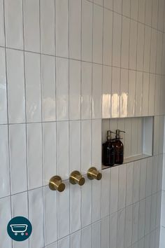 three soap dispensers mounted to the wall in a tiled bathroom with white tiles