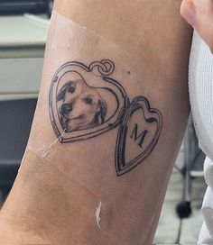 a woman's arm with a dog in a heart shaped frame tattoo on it