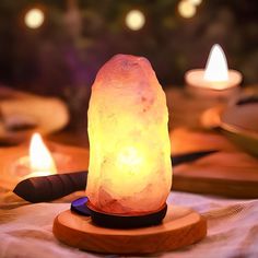 a himalayan salt lamp sitting on top of a wooden stand next to two lit candles