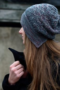 a woman with long hair wearing a knitted beanie hat and looking off into the distance