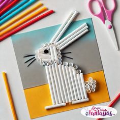 an animal made out of plastic straws on top of a card with scissors and markers