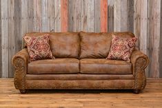 a brown leather couch sitting on top of a hard wood floor next to a wooden wall