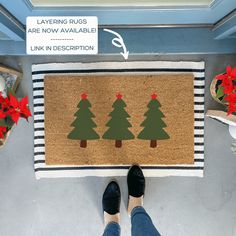 a person standing next to a door mat with christmas trees on it