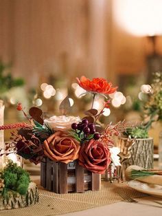 an arrangement of flowers and candles on a table with lights in the backround