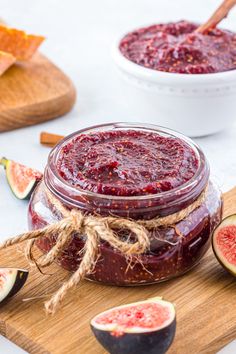 a jar filled with jam sitting on top of a cutting board next to sliced figs