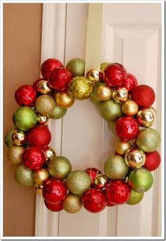 a christmas wreath hanging on the front door with ornaments around it and an ornament in the middle