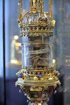 a gold clock with many pieces of jewelry in it's glass dome display case