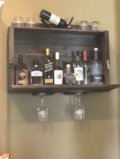 a wooden shelf with liquor glasses and bottles on it