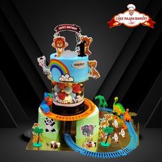 a birthday cake with animals and rainbows on the top is surrounded by toy train tracks