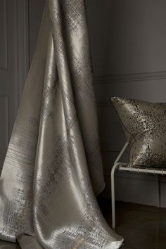 a chair sitting next to a silver curtain