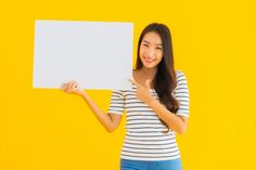 a woman holding up a blank sign against a yellow background with her hand in the air