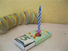 a very cute small birthday cake with a lit candle on it's stand next to a book