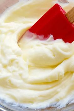 a red spatula mixing cream in a bowl