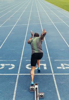 a man running on a track with his hands up in the air, from above