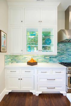 a kitchen with white cabinets and wood floors