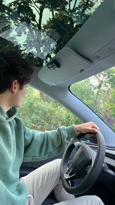 a man sitting in the driver's seat of a car with his hands on the steering wheel