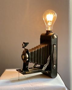 an old fashioned camera with a light bulb on it's head sitting on top of a table